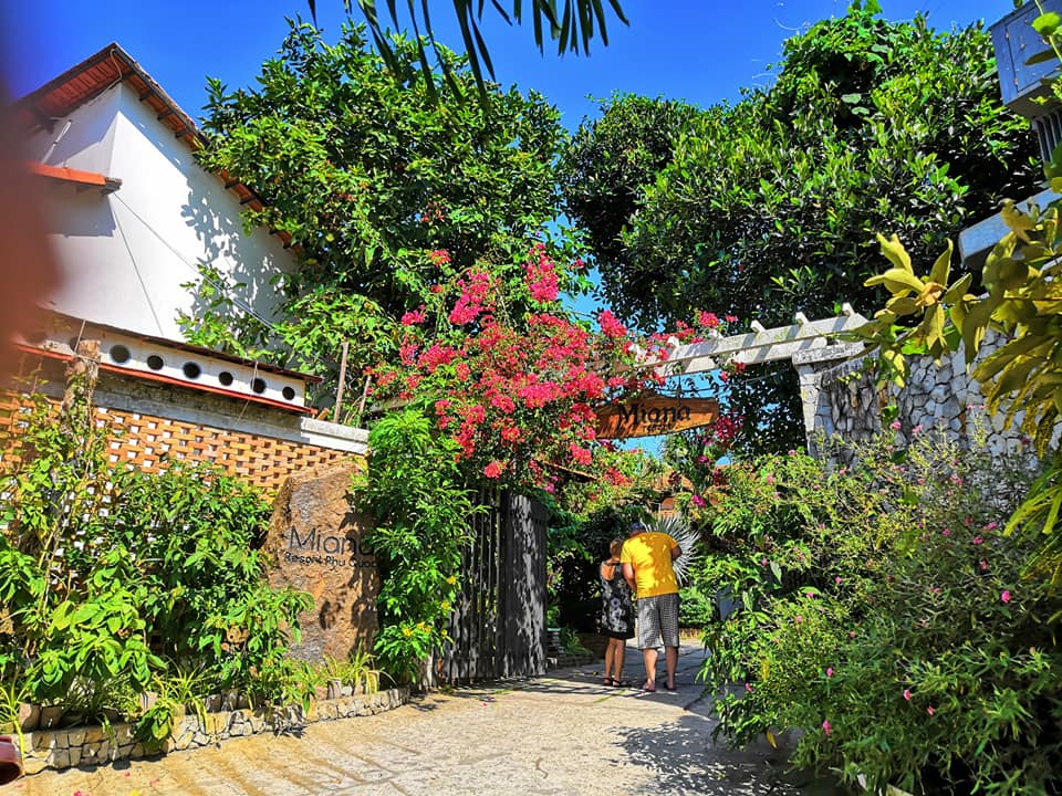 Cổng của Miana Resort Phú Quốc với cây cối xanh tươi và điểm xuyến thêm nhiều bông hoa đầy màu sắc